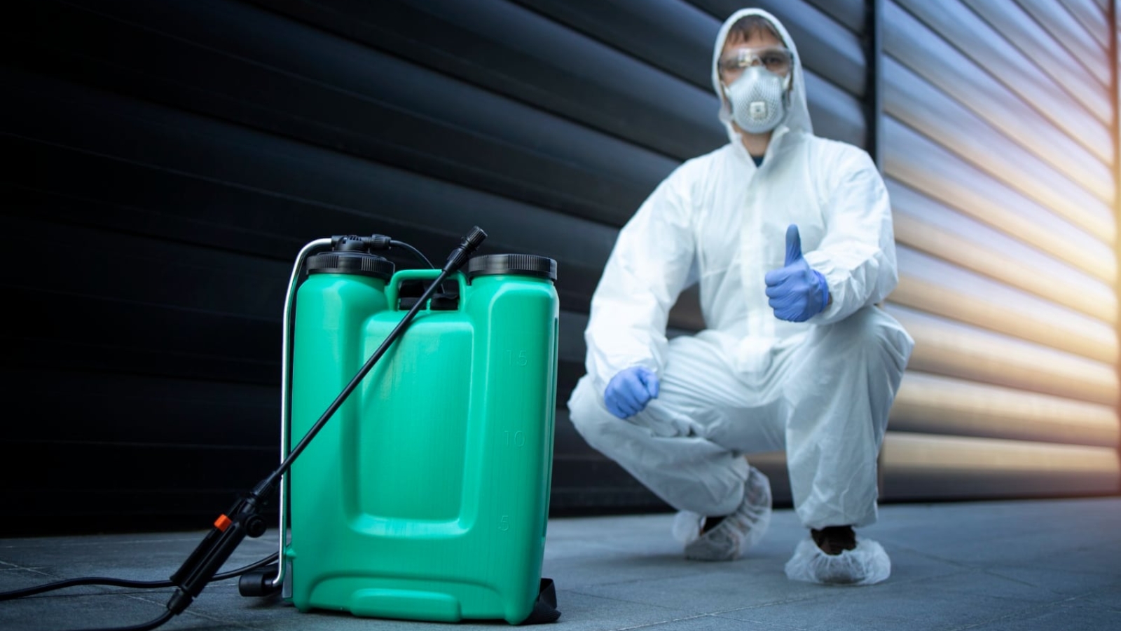 exterminator-white-protective-uniform-standing-by-reservoir-with-chemicals-sprayer