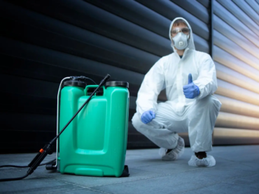 exterminator-white-protective-uniform-standing-by-reservoir-with-chemicals-sprayer